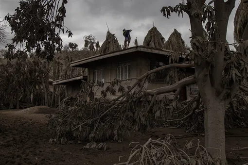 LAUREL, PHILIPPINES — JANUARY 14: A resident cleans a house rooftop of volcanic ash from Taal Volcano's eruption on January 14, 2020 in Laurel, Batangas province, Philippines. The Philippine Institute of Volcanology and Seismology raised the alert level to four out of five, warning that a hazardous eruption could take place anytime, as authorities have evacuated tens of thousands of people from the area. An estimated $10 million worth of crops and livestock have been damaged by the on-going eruption, according to the country's agriculture department. (Photo by Ezra Acayan/Getty Images)