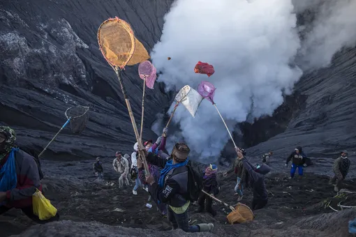 TOPSHOT-INDONESIA-CULTURE-RELIGIONTOPSHOT — People try to catch offerings thrown by Tengger tribe people off the summit of the active Mount Bromo volcano in Probolinggo, East Java province on June 26, 2021, during the Yadnya Kasada festival to seek blessings from the main deity by presenting offerings of rice, fruit, livestock and other items. (Photo by )