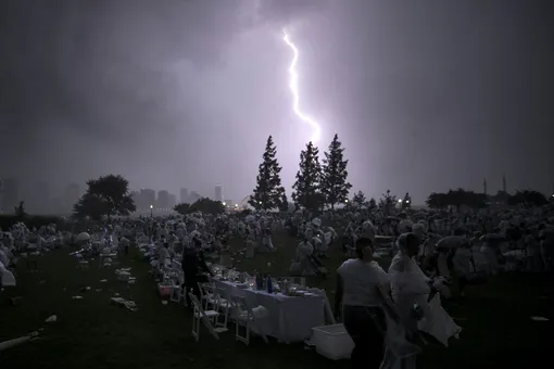 Участники «Ужина в белом» наблюдают удар молнии в Рокфеллер-парке в Нью-Йорке.
