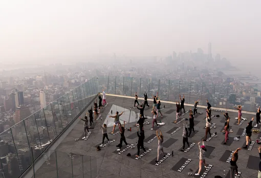 Коасс по йоге проходит на смотровой площадке The Edge. Манхэттен окутан смогом, 7 июня 2023 года