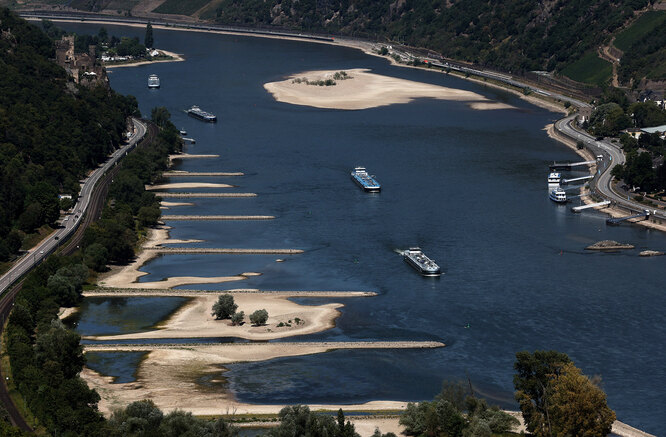 Transport vessels cruise past the partially dried riverbed of the Rhine river in Bingen, Germany, August 9, 2022. REUTERS/Wolfgang Rattay