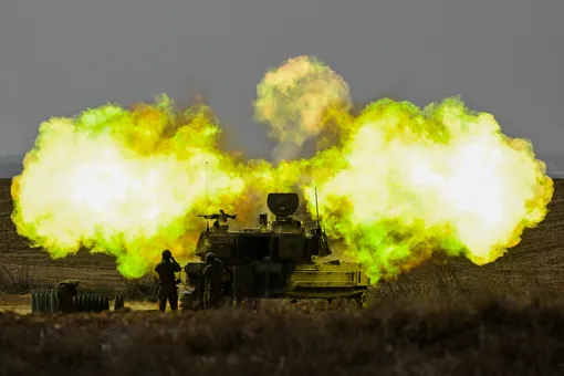 Солдат артиллерии ЦАХАЛ затыкает уши во время взрыва снаряда, выпущенного в сторону сектора Газа, 11 октября 2023 года, недалеко от Нетивота, Израиль