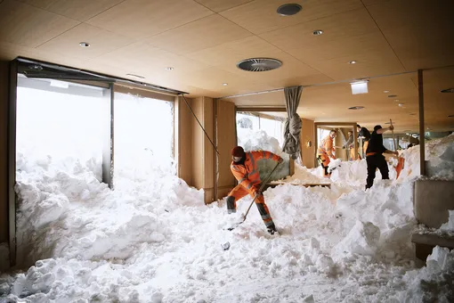 Уборка снега в номерах отеле Saentist в Швегальпе, Швейцария, 11 января 2019. По сообщениям полиции, три человека в городе получили легкие ранения из-за схода лавины в этот день.