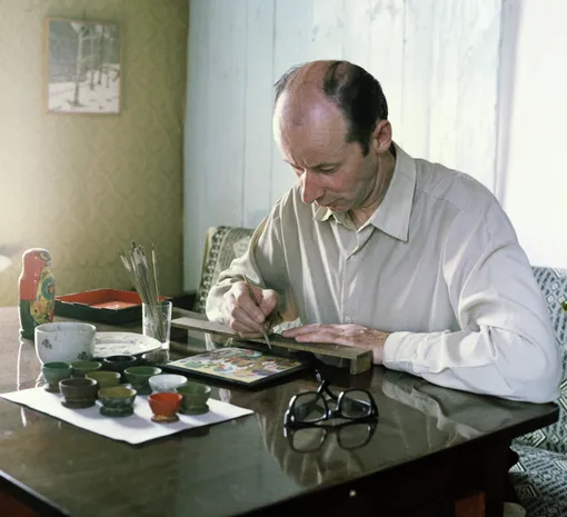 Художник Н. И. Шишаков расписывает крышку шкатулки в своей мастерской