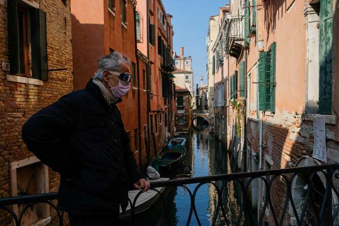 citizen wearing a protective mask is seen on a bridge on the second day of an unprecedented lockdown across of all Italy imposed to slow down the outbreak of coronavirus, in Venice, Italy, March 11, 2020.
