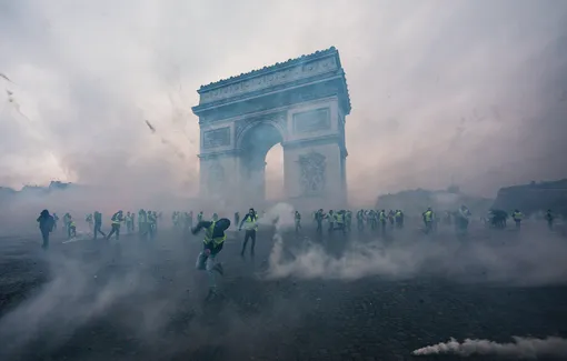 Облако слезоточивого газа вокруг протестующих и силовиков во время демонстрации «Желтых жилетов» возле Триумфальной арки 1 декабря 2018 в Париже