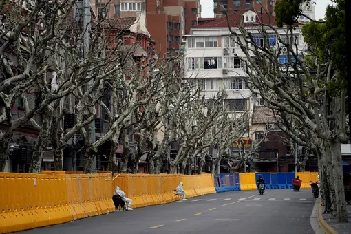 Workers in protective suits keep watch next to barricades of a sealed-off area, following the coronavirus disease (COVID-19) outbreak in Shanghai, China March 30, 2022. REUTERS/Aly Song