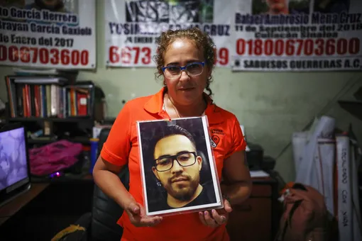 Maria Isabel Cruz Bernal, founder of Sabuesos Guerros, holds up a photo of her son, Yosimar Garcia, who has been missing for several years.