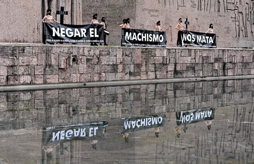 Фем-активистки держат баннеры с надписью «Отрицание сексизма убивает нас» на площади Плаза-де-Колон в Мадриде, Испания.