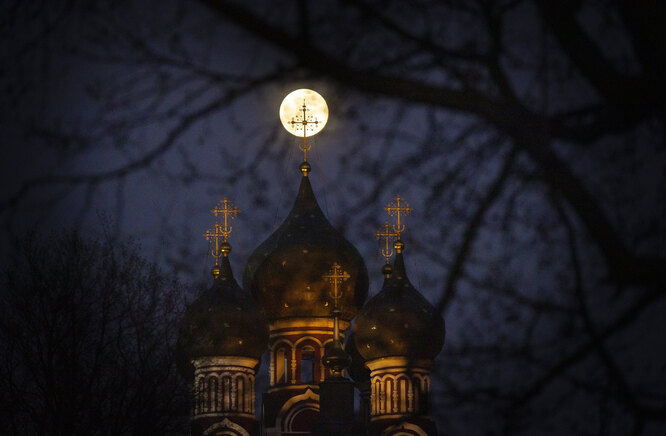 Суперлуна освещает крест церкви в Москве
