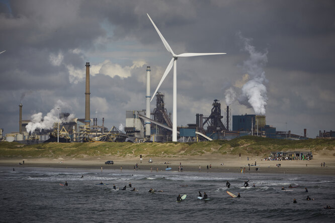 Серферы на фоне сталелитейного Tata Steel, угрожающего окружающей среде, пирса 20 августа 2021 года в Велсен-Ноорде. Сталелитейный завод Tata находится под следствием голландской