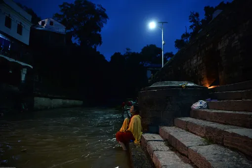 Жительница Катманду купается в реке Багмати в частичное лунное затмение, Непал